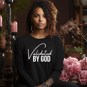 May include: A black long-sleeved shirt with the text "Validated by God" in white cursive lettering.