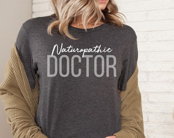 May include: A dark gray t-shirt with the text "Naturopathic DOCTOR" in white lettering.