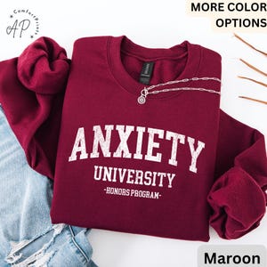 May include: Maroon sweatshirt with the text "Anxiety University - Honors Program" in white.