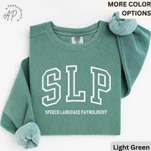 May include: Light green sweatshirt with the text "SLP" in white outlined letters and the words "Speech Language Pathologist" below.