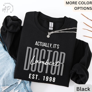 May include: Black sweatshirt with the text "Actually, it's Doctor Lambert Est. 1998" in gray lettering.