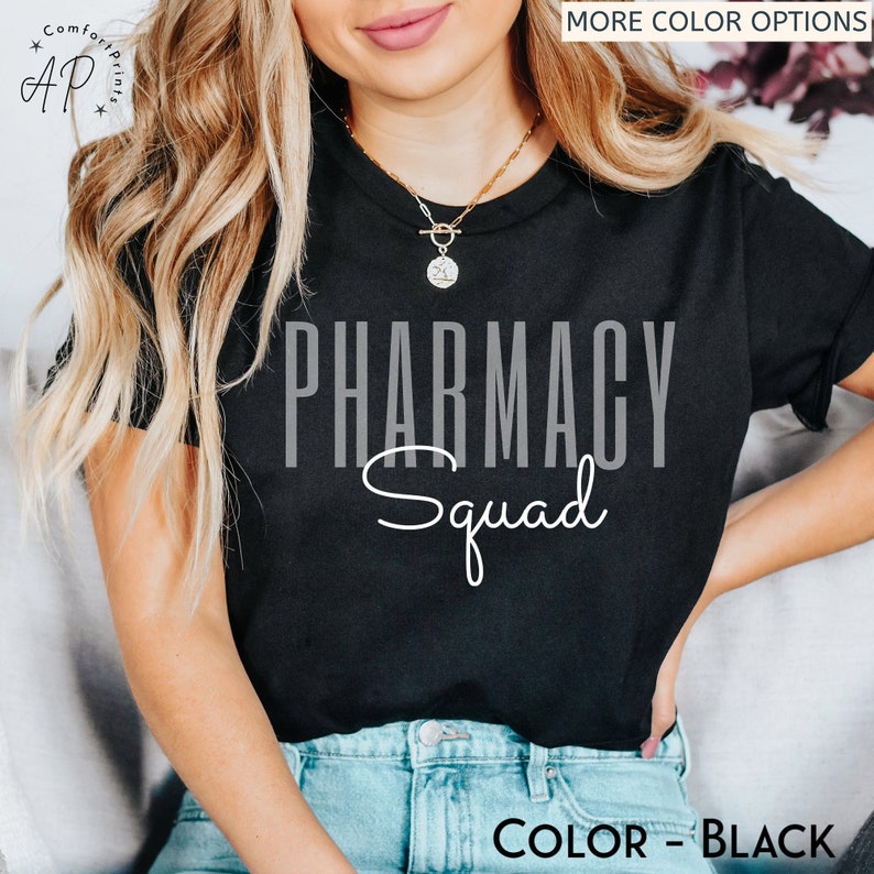 May include: Black t-shirt with the text "Pharmacy Squad" in white and gray lettering. The shirt is being worn by a person with long blonde hair.