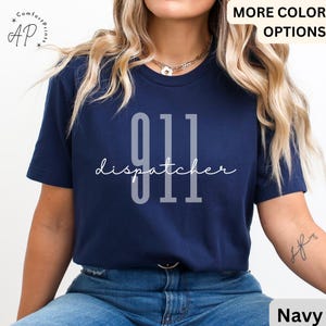 May include: Navy blue t-shirt with the text "911 dispatcher" in white. The numbers are large and bold.