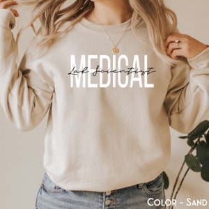 May include: A sand-colored sweatshirt with the text "MEDICAL Lab Scientist" printed in white.