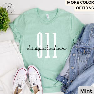 May include: A mint green t-shirt with the text "911 dispatcher" in white and black lettering.