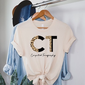 May include: A beige t-shirt with a black and leopard print "CT" design. The text "Computed Tomography" is written below the design.