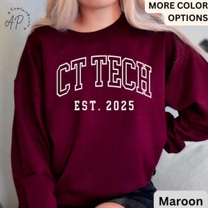 May include: Maroon sweatshirt with the text "CT TECH EST. 2025" in white block letters. The sweatshirt has a crew neck and long sleeves. The image also includes the words "MORE COLOR OPTIONS" and the color "Maroon".