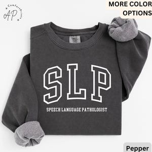 May include: A dark gray sweatshirt with the text "SLP" in white, outlined in black, and the words "Speech Language Pathologist" in white below.