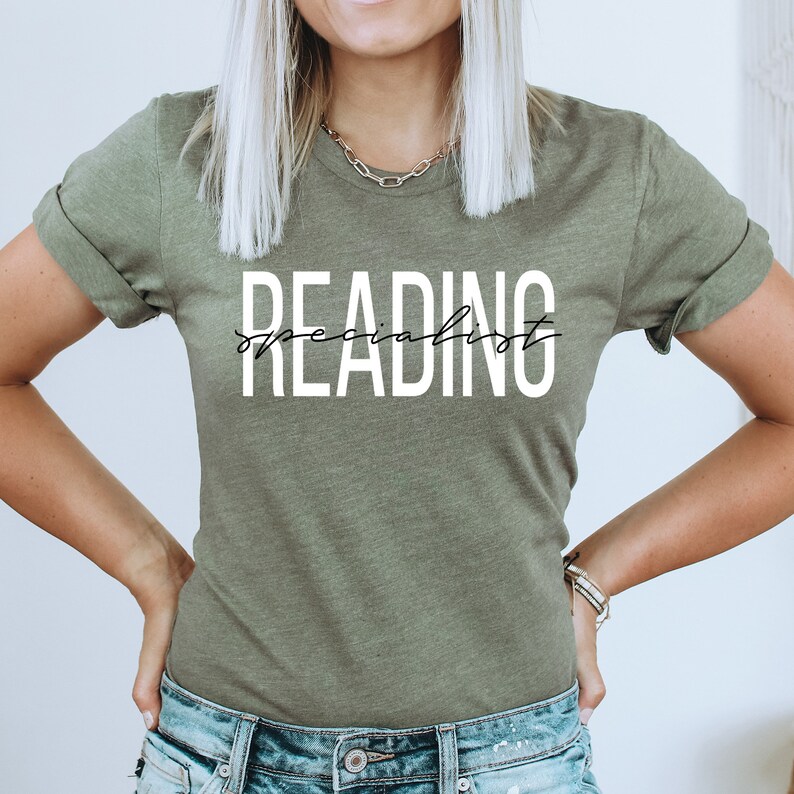 Puede incluir: Una camiseta verde con el texto "READING specialist" en letras blancas con escritura cursiva negra.