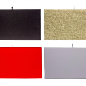 May include: Four rectangular boxes in a grid, each with a different surface. The top left is black, the top right is tan with a woven texture, the bottom left is red, and the bottom right is light gray. Each has a small loop.