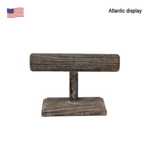May include: A wooden bangle display stand with a distressed white finish. The stand has a rectangular base and a round top.