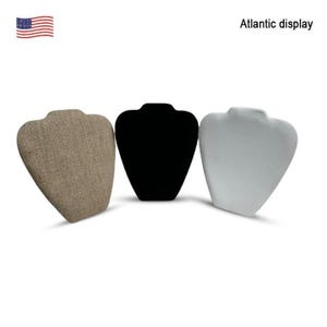 May include: Three necklace display busts in different colors. One is a light brown fabric, the second is black, and the third is white. The text "Atlantic display" is visible in the upper right corner. An American flag is in the upper left corner.