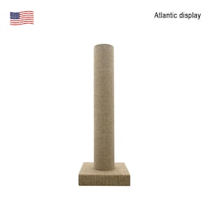 May include: A beige fabric-covered display stand with a cylindrical column and a square base. The stand is designed for displaying jewelry or other small items.