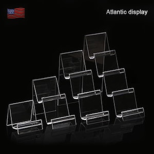 May include: Set of seven clear acrylic display stands, arranged in a pyramid shape. The stands are designed to hold small items, such as phones, jewelry, or other accessories.  Atlantic display.