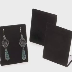 May include: Black velvet earring display stands. One stand displays two silver filigree earrings with teardrop-shaped, light blue accents. Two additional stands are visible, showcasing the product's presentation options. The stands are designed to showcase jewelry.