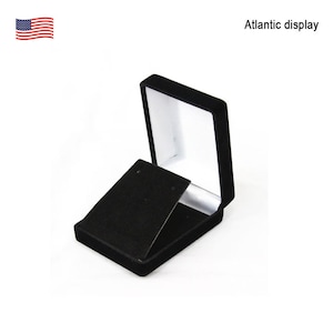 May include: Black velvet jewelry box with a hinged lid and a white interior. The box is designed to hold a pair of earrings.