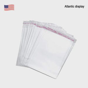 May include: A stack of clear, self-sealing cellophane bags with a red and white printed strip along the top edge. The bags are arranged in a fan shape, with the text "Atlantic display" visible.