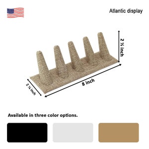 May include: A beige ring display with five ring holders. The display is 8 inches long and 2 1/2 inches wide. Available in three colors: black, white, and beige.