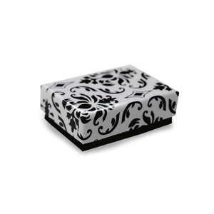 May include: A small, white gift box with a black and white damask pattern. The box has a black lid and a white base.