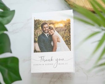 May include: A white thank you card with a photo of a bride and groom. The text on the card reads "Thank you" with the names "Joseph & Sophie" and the date "18.06.23" below the photo.