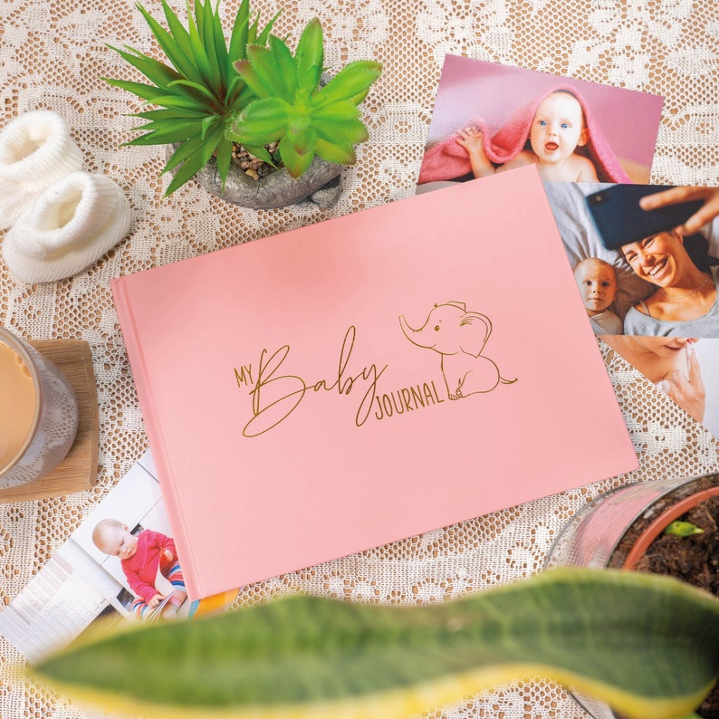 Puede incluir: Un diario de beb&eacute; rosa con una ilustraci&oacute;n de elefante dorada y el texto "My Baby Journal".