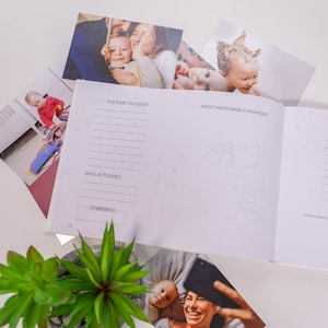 Puede incluir: Un libro de recuerdos de baby shower blanco con un dise&ntilde;o rosa y blanco. El libro tiene secciones para "La Baby Shower", "Momento m&aacute;s memorable", "Qui&eacute;nes asistieron", y "Fecha".