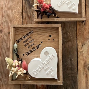 May include: Two wooden boxes with white heart-shaped plaques. The top box has the text "Kleine Menschen brauchen so grosse Herzen wie Ihres Danke f&uuml;r alles Lehrerin mit Herz". The bottom box has the text "Kleine Menschen brauchen so grosse Herzen wie Deins Danke f&uuml;r alles Erzieherin mit Herz".