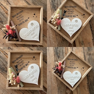 May include: Four wooden boxes with a heart-shaped plaque inside each. The plaques are white and have the words "Erzieherin mit Herz" and "Lehrerin mit Herz" written on them. The boxes also contain a small candle and dried flowers.