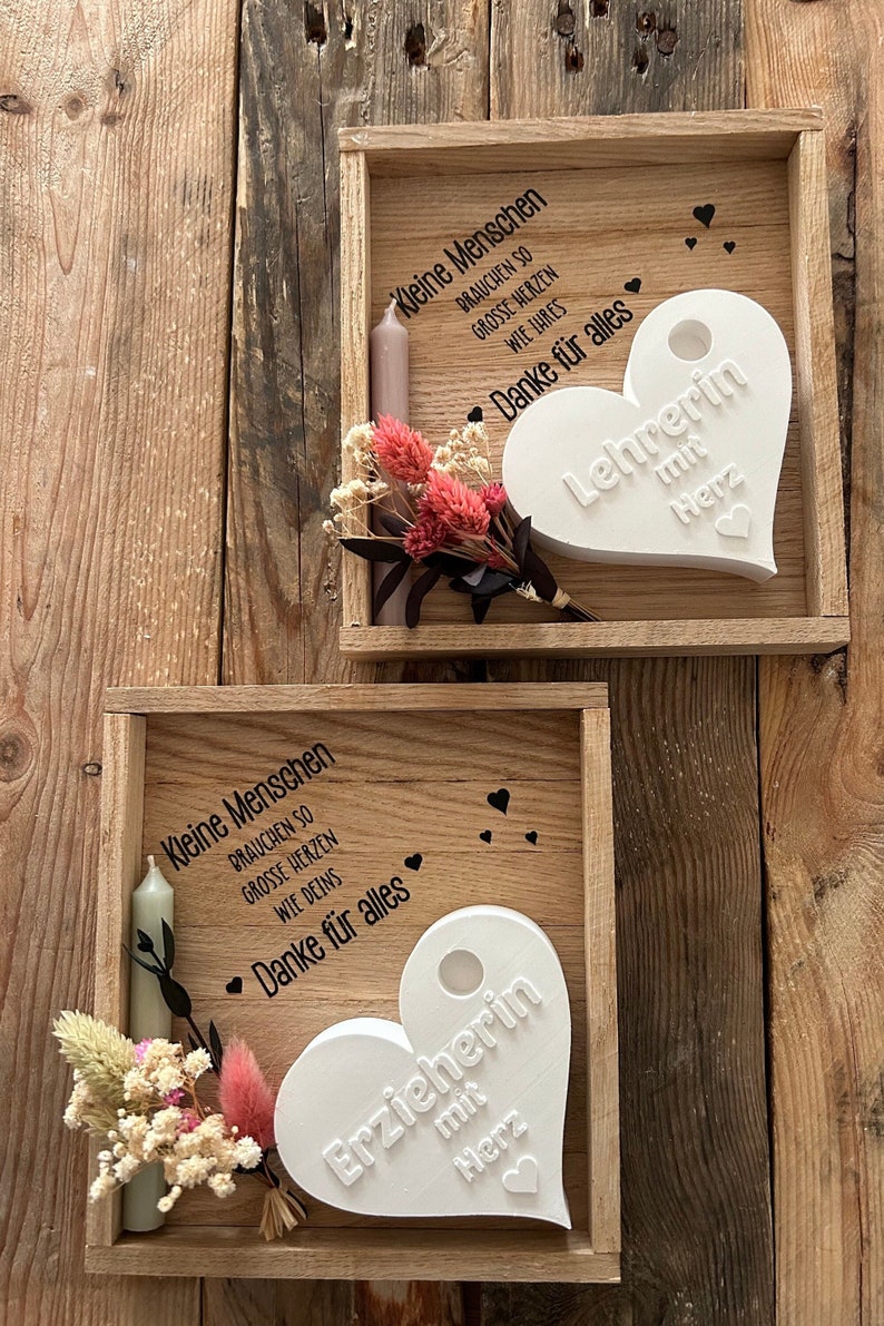 May include: Two wooden boxes with white heart-shaped plaques. The top box has the text "Kleine Menschen brauchen so grosse Herzen wie Ihres Danke f&uuml;r alles Lehrerin mit Herz". The bottom box has the text "Kleine Menschen brauchen so grosse Herzen wie Deins Danke f&uuml;r alles Erzieherin mit Herz".