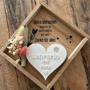 May include: A wooden tray with a white heart-shaped plaque that says "Lehrerin mit Herz" (Teacher with Heart). The tray also has a small bouquet of dried flowers and a white candle.