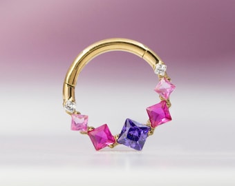 May include: Gold hoop earring with a row of colorful gemstones. The gemstones are pink, purple, and clear.