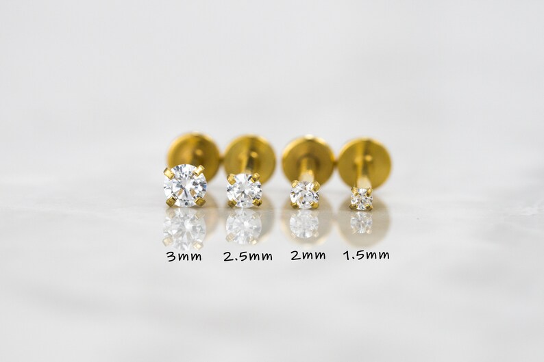 May include: Four gold-toned stud earrings with clear round stones. The stones are 3mm, 2.5mm, 2mm, and 1.5mm in size.