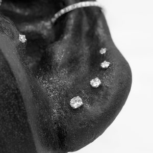 May include: Close-up of a black surface with five small, clear, round rhinestones.