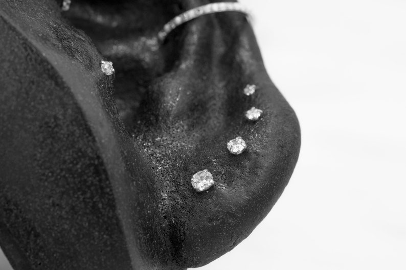 May include: Close-up of a black surface with five small, clear, round rhinestones.