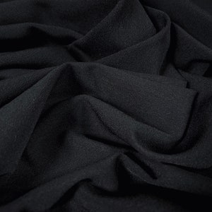 May include: Black fabric with a soft, textured surface. The fabric is draped and folded, creating a smooth, flowing look.