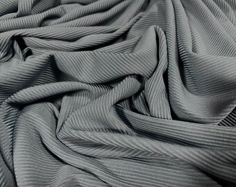 May include: Close-up of a gray ribbed fabric with a soft, textured surface. The fabric is folded and draped, showcasing its flexibility and drape.