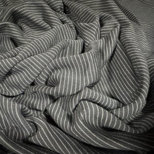 May include: A close-up of a grey and white striped fabric with a textured surface. The fabric is folded and draped, creating a soft and inviting look.