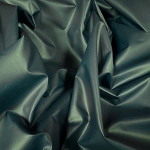 May include: Close-up of teal fabric with a satin sheen. The material is heavily draped, creating deep folds and shadows that highlight its texture. The fabric's surface reflects light, giving it a luxurious appearance. Suitable for apparel or home decor.