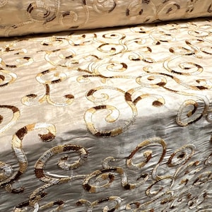 May include: Beige fabric with a swirl pattern embroidered in brown and gold thread.