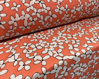 May include: Coral pink fabric with a white floral pattern. The fabric is sheer and lightweight.