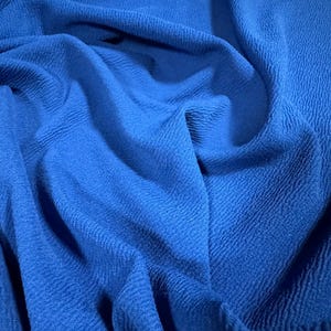 Könnte beinhalten: Nahaufnahme eines strukturierten blauen Stoffes. Der Stoff hat eine weiche, leicht gewellte Textur.