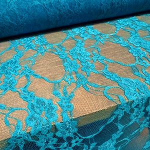 May include: Teal blue lace fabric with a floral pattern. The lace is delicate and has a soft, flowing texture.