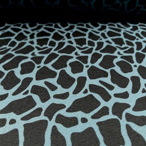 May include: A close-up of a black and light blue fabric with a repeating pattern of irregular shapes. The fabric has a textured surface.