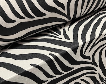 May include: Black and white zebra print fabric. The fabric has a textured surface and is folded in half.