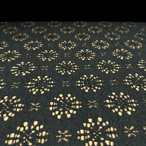 May include: Black fabric with a repeating pattern of small, beige, floral shapes.