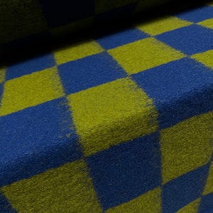 May include: A checkered fabric with alternating squares of dark blue and olive green. The fabric has a fuzzy texture.
