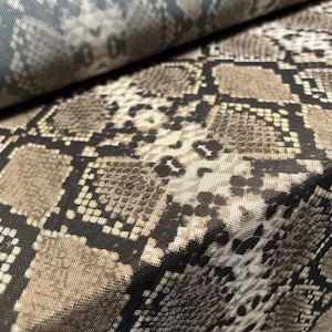 Könnte beinhalten: Nahaufnahme eines braunen und schwarzen Schlangenlederstoffs mit einem sich wiederholenden Muster. Der Stoff hat eine strukturierte Oberfläche und einen dezenten Glanz.