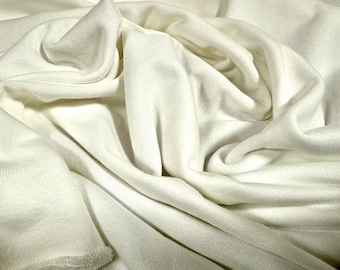 May include: A close-up of a white fabric with a soft, smooth texture. The fabric is draped and folded, creating a sense of movement and flow.