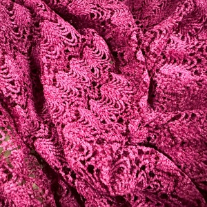 May include: Close-up of a deep pink lace fabric with a delicate floral pattern.