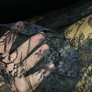 May include: Black lace fabric with a delicate floral pattern. The lace is soft and sheer, and it has a slightly textured surface.